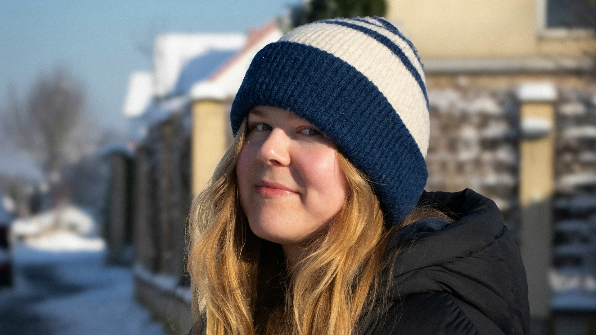 a woman standing in the snow in front of a house