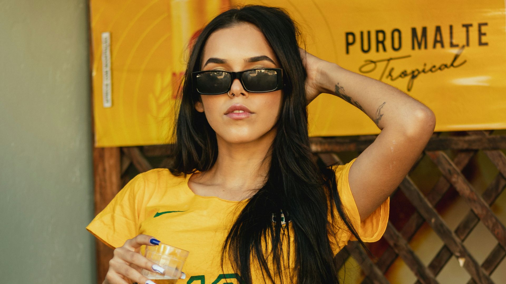 a person sitting on a chair holding a drink and posing for the camera