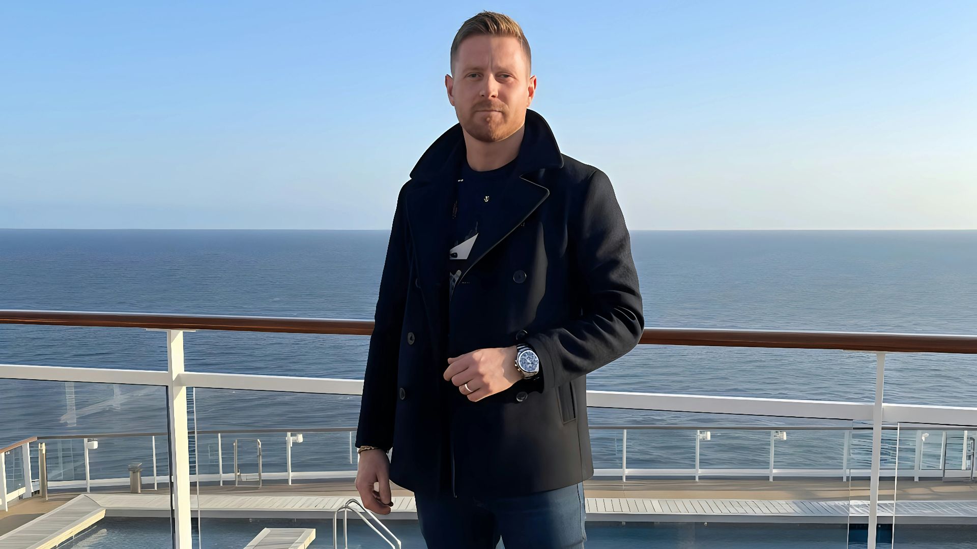Man in peacoat and jeans on ship deck