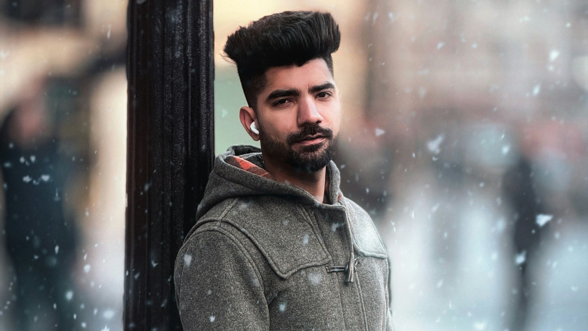 Man leaning against lamppost in falling snow