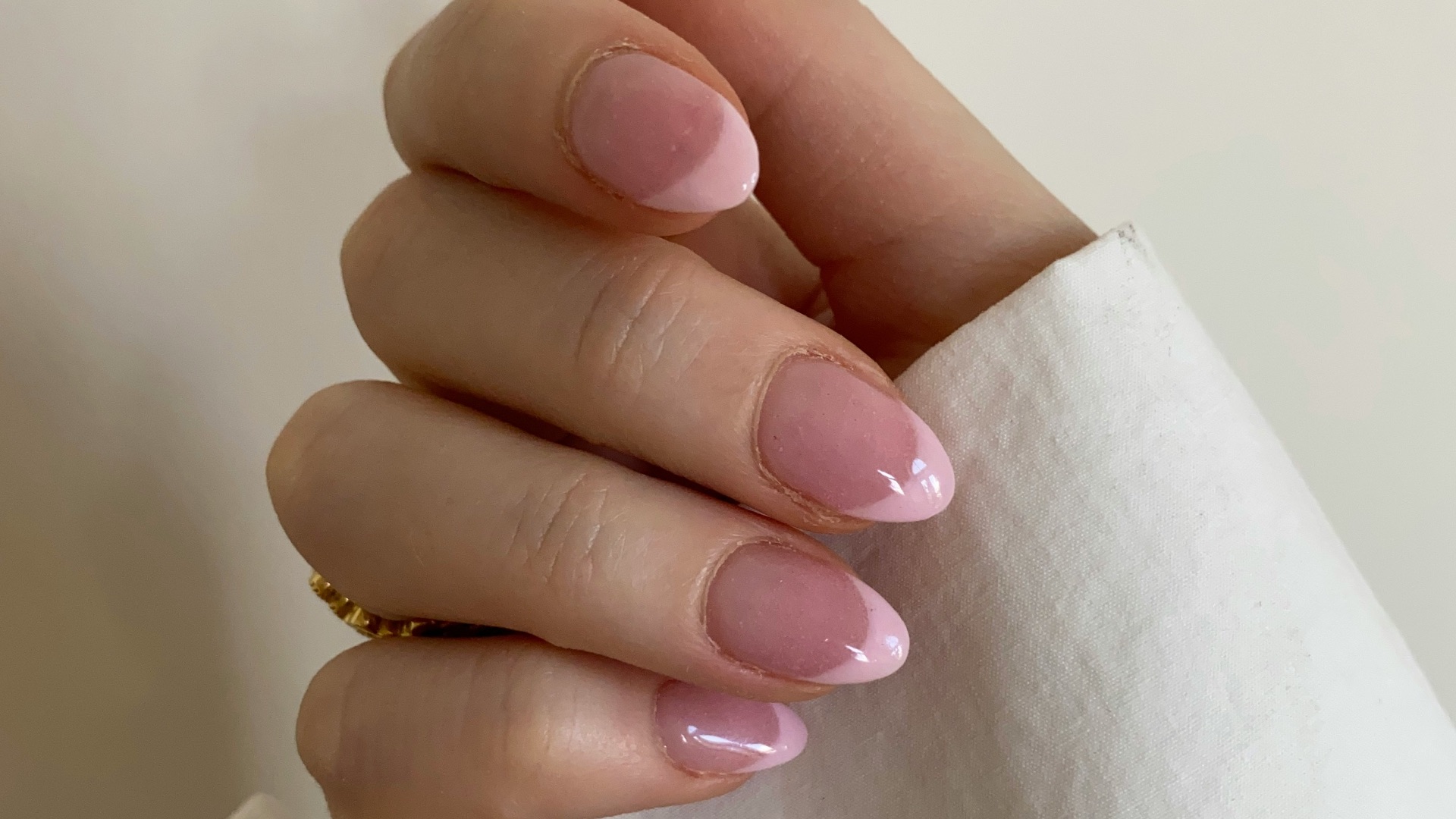 person with pink manicure on white textile