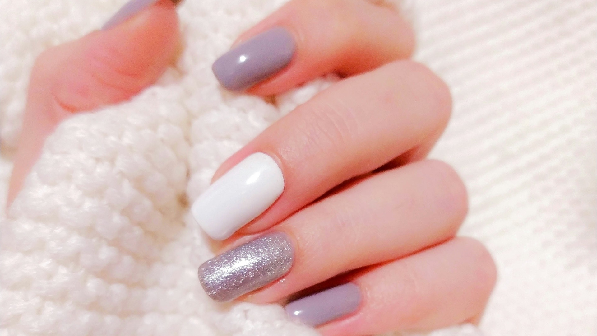 person with pink manicure on white textile