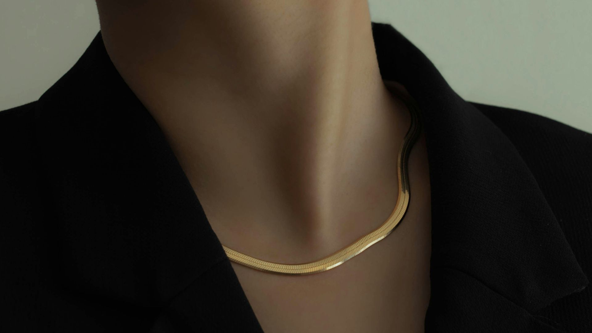 woman in black blazer wearing gold necklace