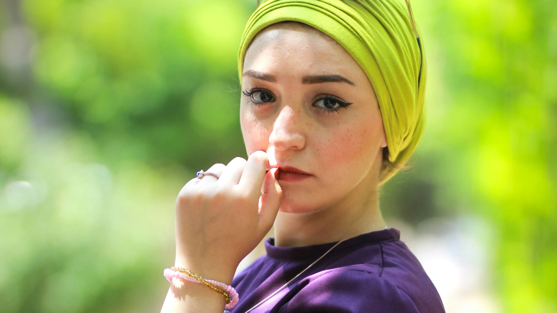 woman wearing purple long-sleeved top holding her lips during daytime