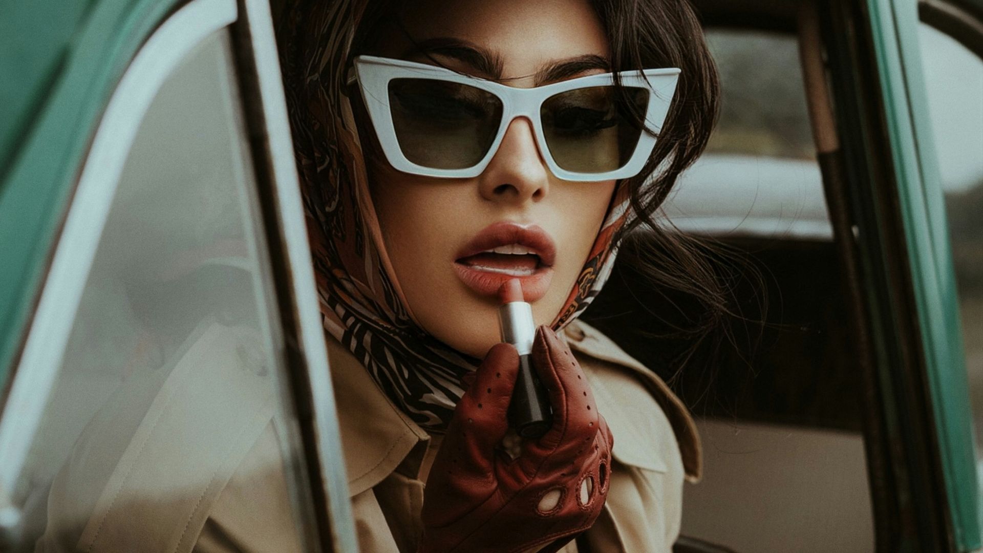 a woman in sunglasses smoking a cigarette in a car