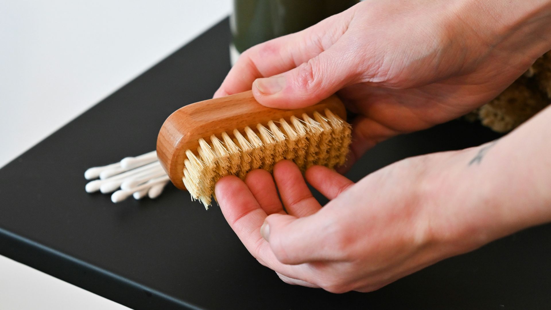 a person holding a wooden brush on top of a table