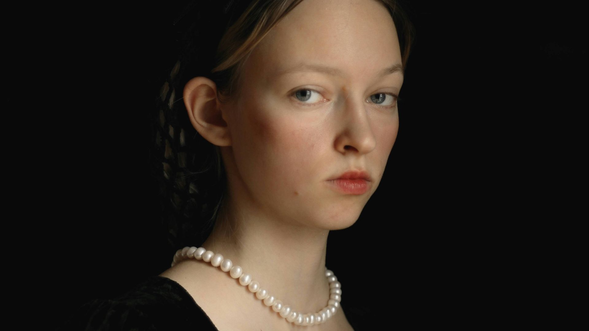 a woman in a black dress with a pearl necklace