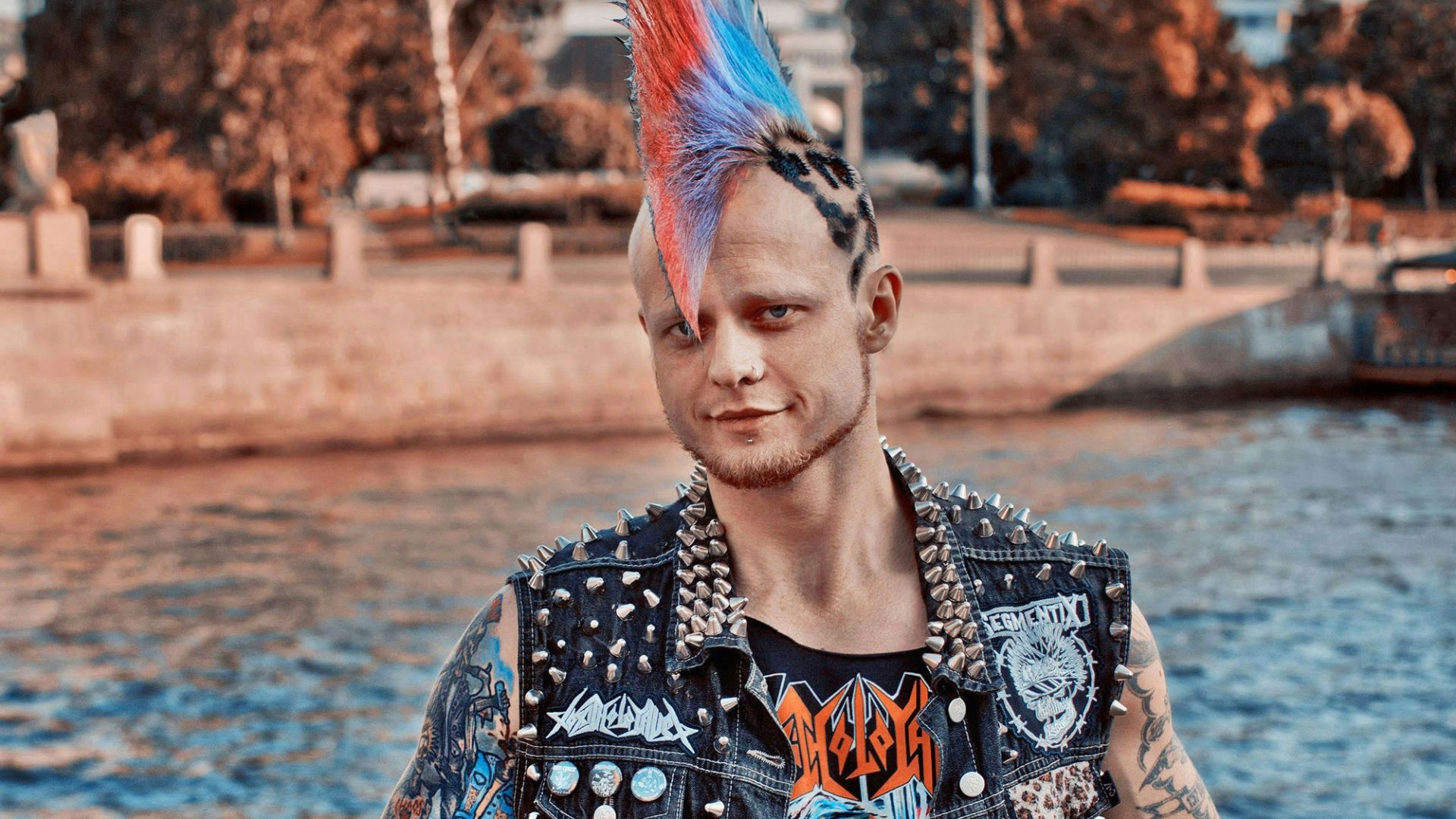 A man with a mohawk standing by the water
