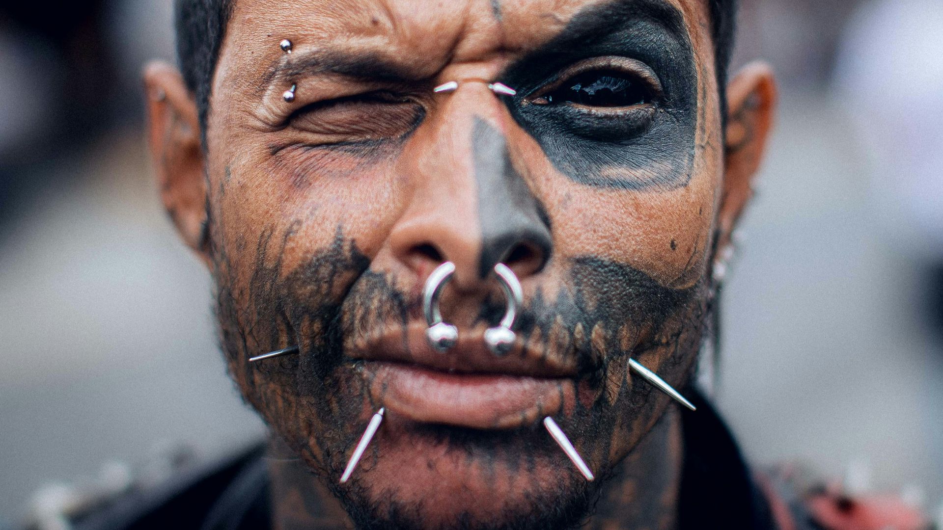 a man with black face paint and piercings on his nose