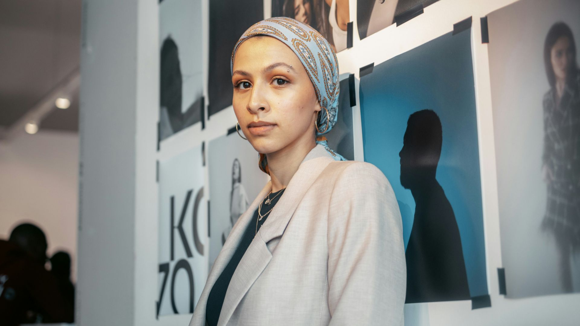 a woman standing in front of a wall with pictures on it