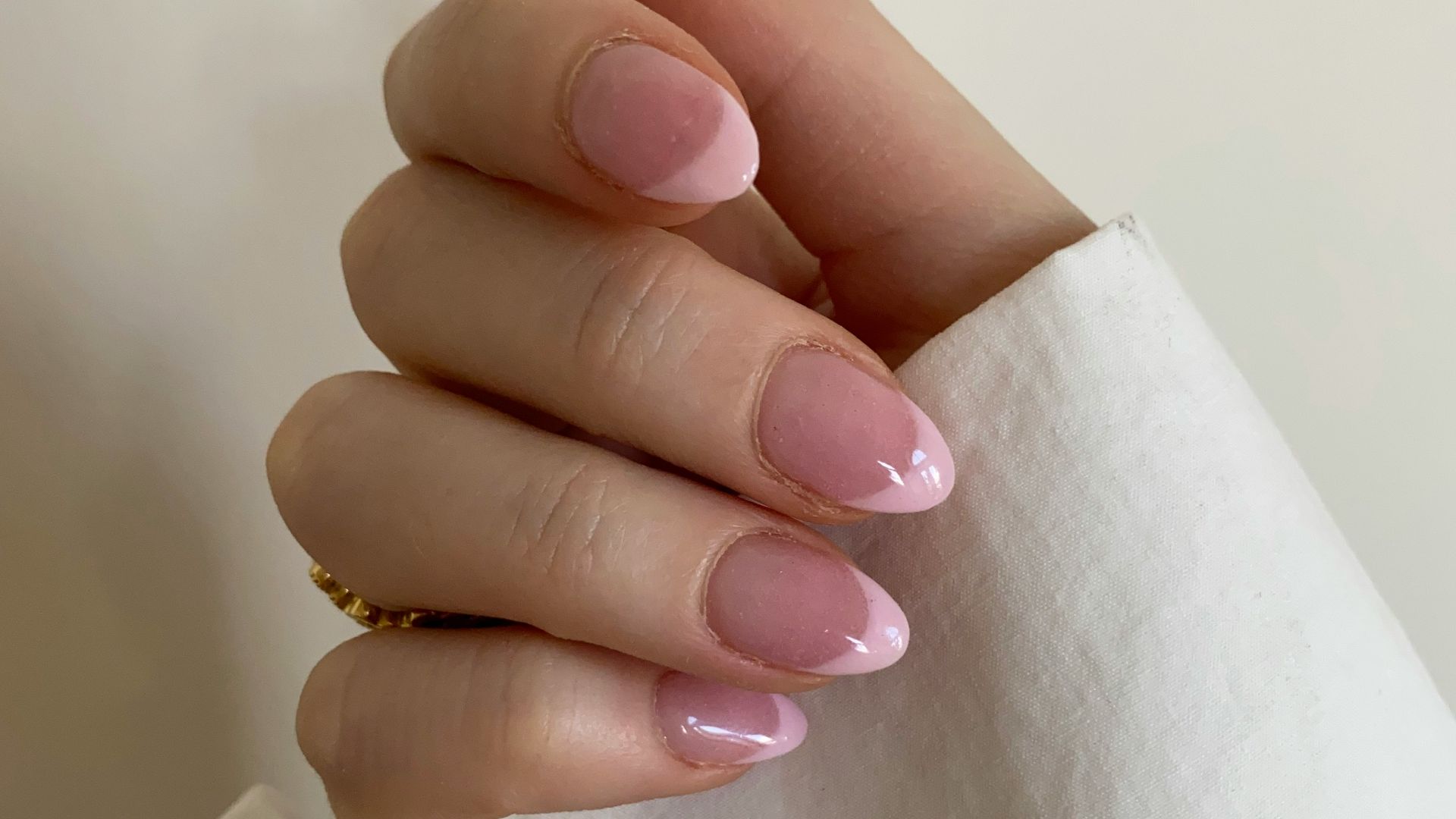 person with pink manicure on white textile