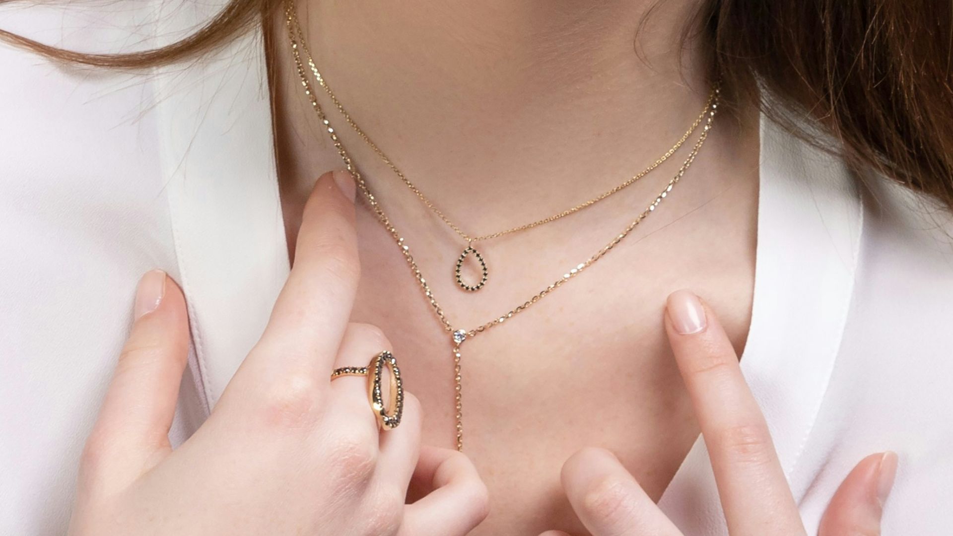 a close up of a person wearing rings and a necklace