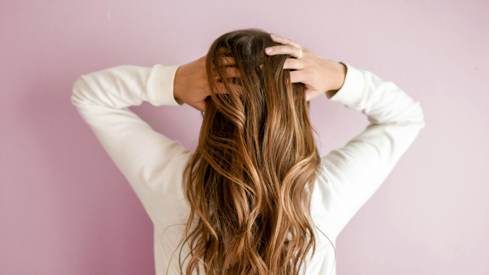 woman in white long-sleeved shirt standing in front of pink wall