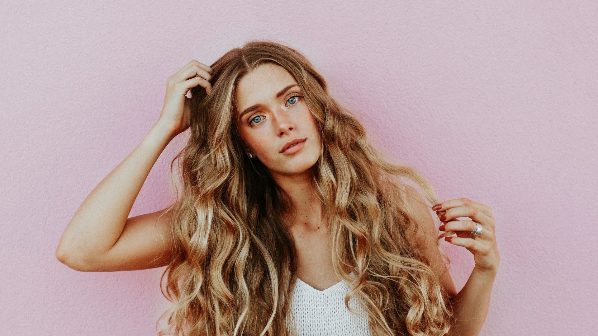woman standing next to pink wall while scratching her head