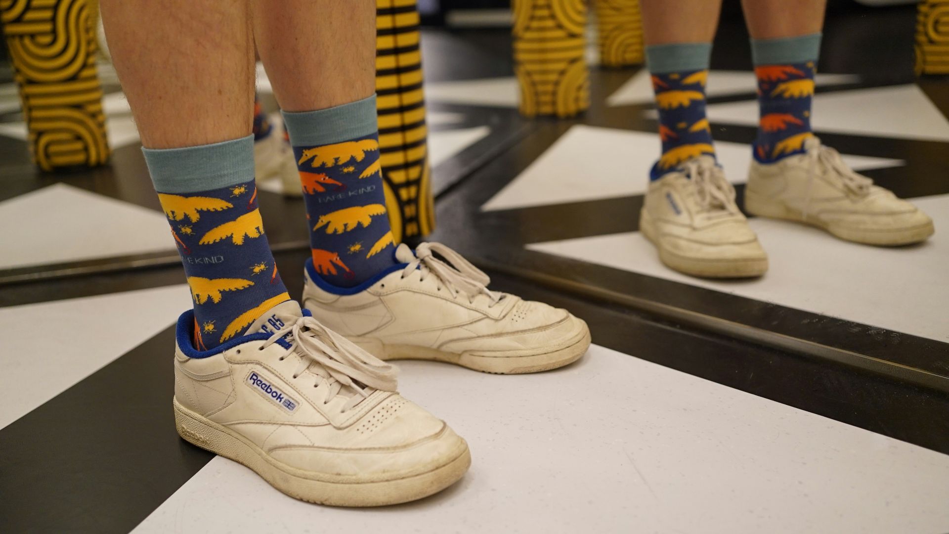 A pair of legs with colorful socks standing in front of a mirror