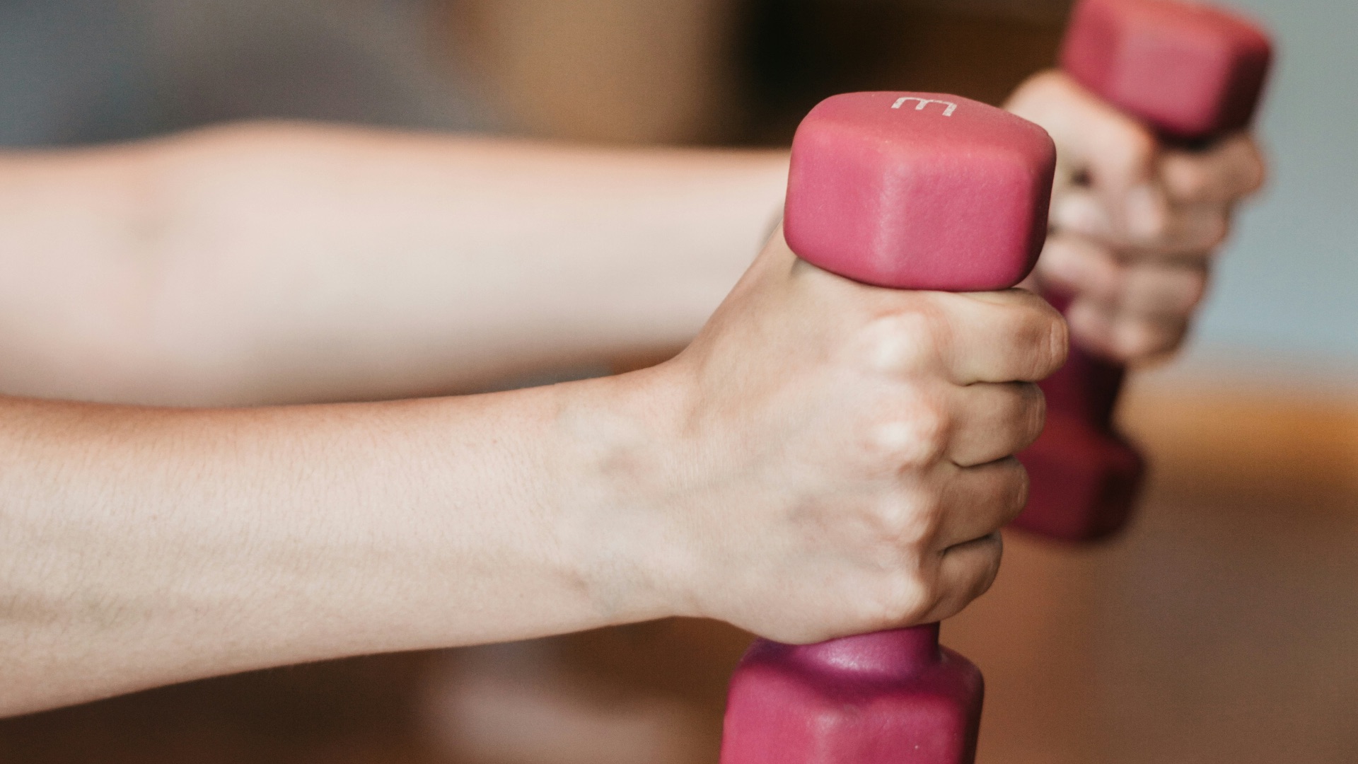 person holding pink and white dumbbells