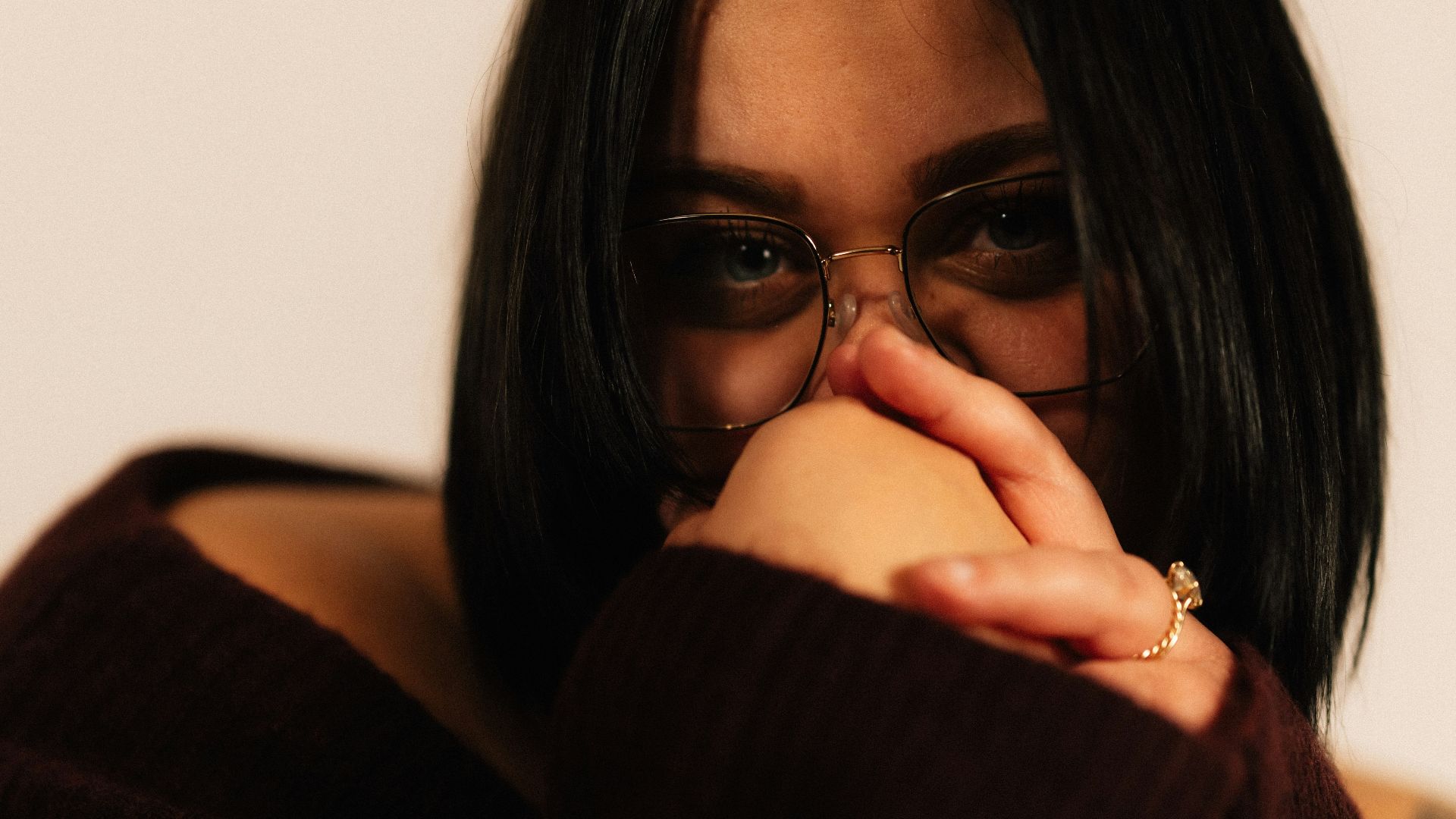 Young woman with dark hair wearing glasses and sweater.