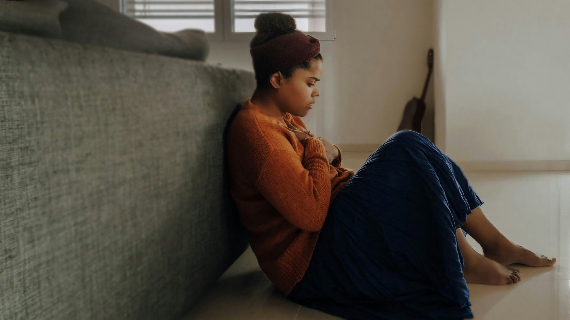 man in orange long sleeve shirt sitting on gray couch