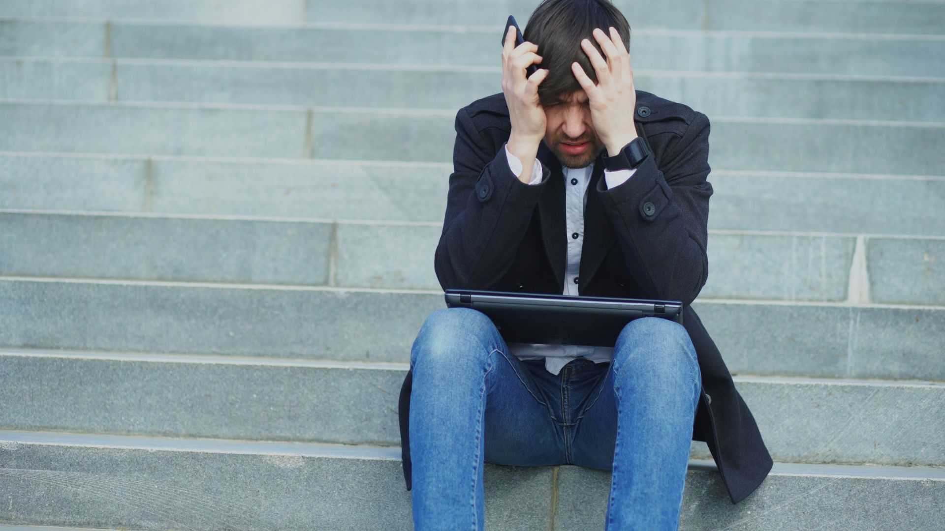 Man sitting on steps with head in hands