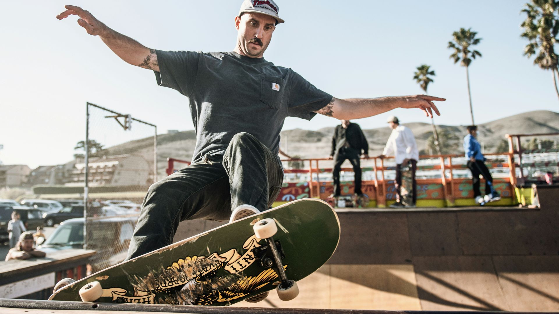 man in black crew neck t-shirt and black pants sitting on skateboard during daytime