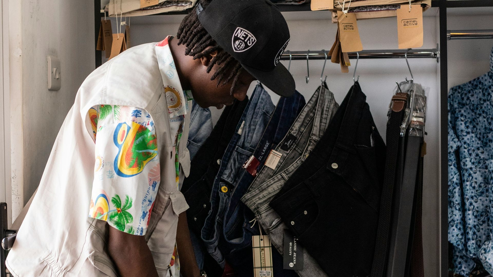 A man standing in front of a closet filled with clothes