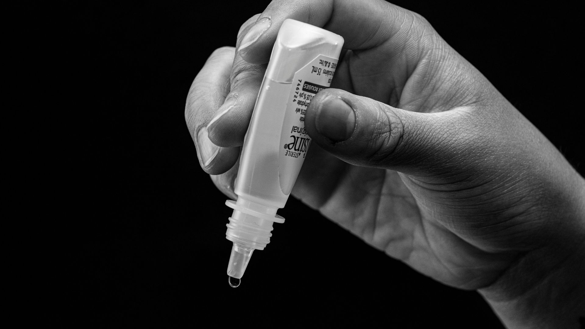 Hand holding eye drops, ready to administer.