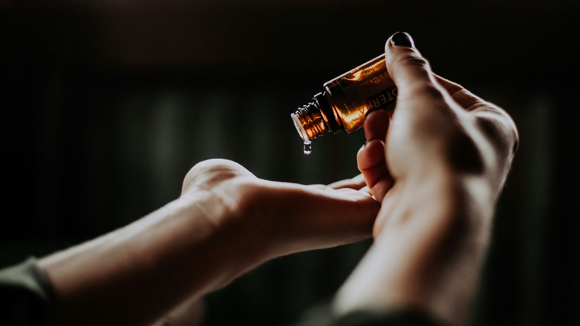 person holding amber glass bottle