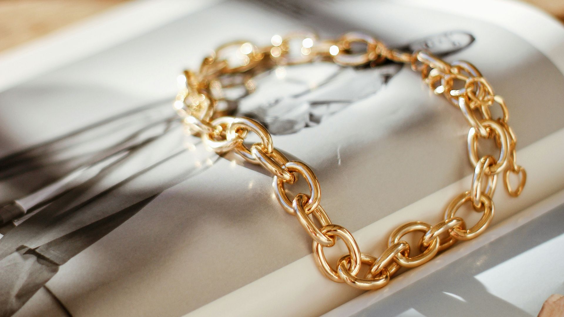 a gold chain bracelet sitting on top of a magazine