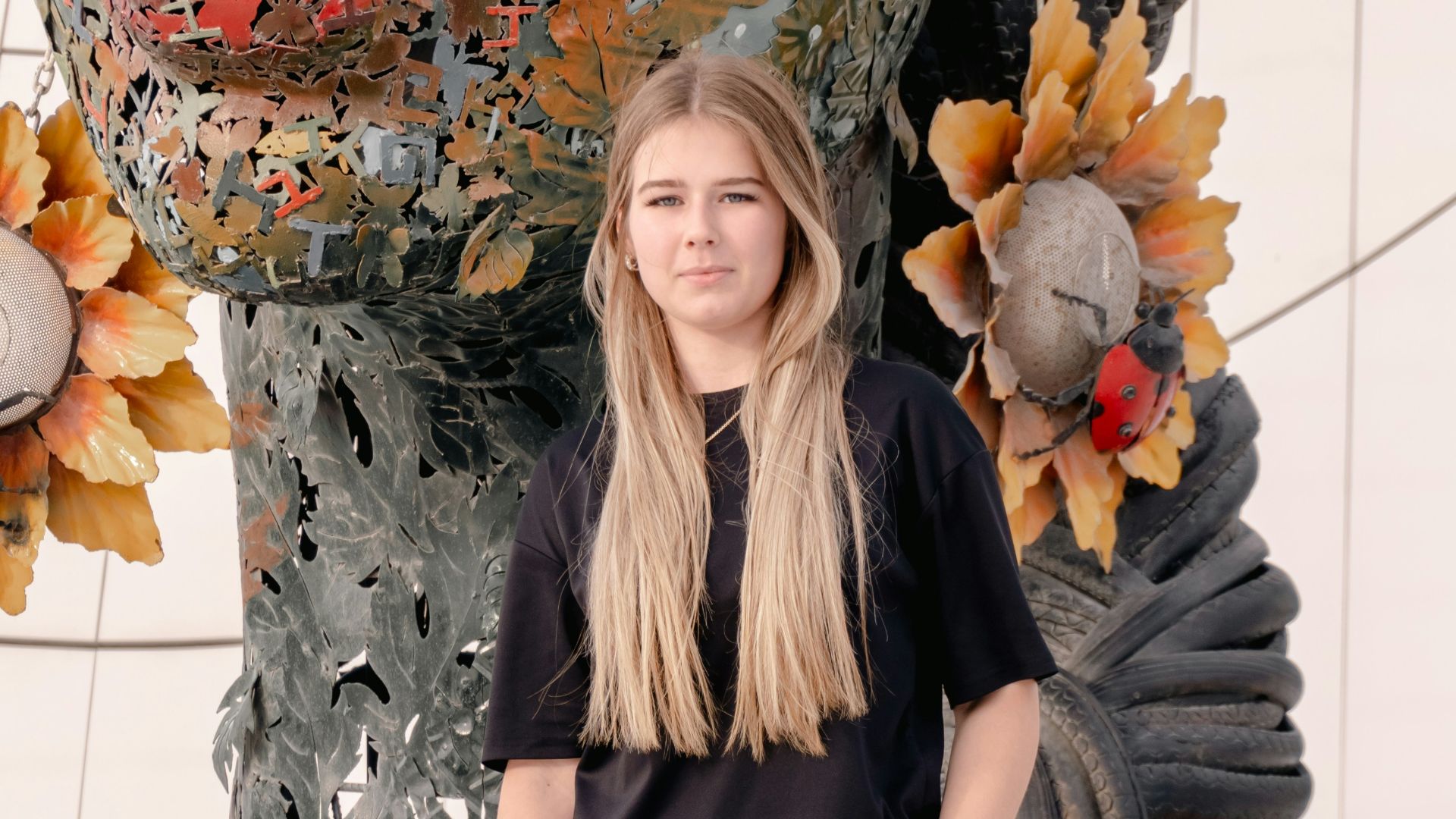 Young woman standing near large artistic sculpture of a face