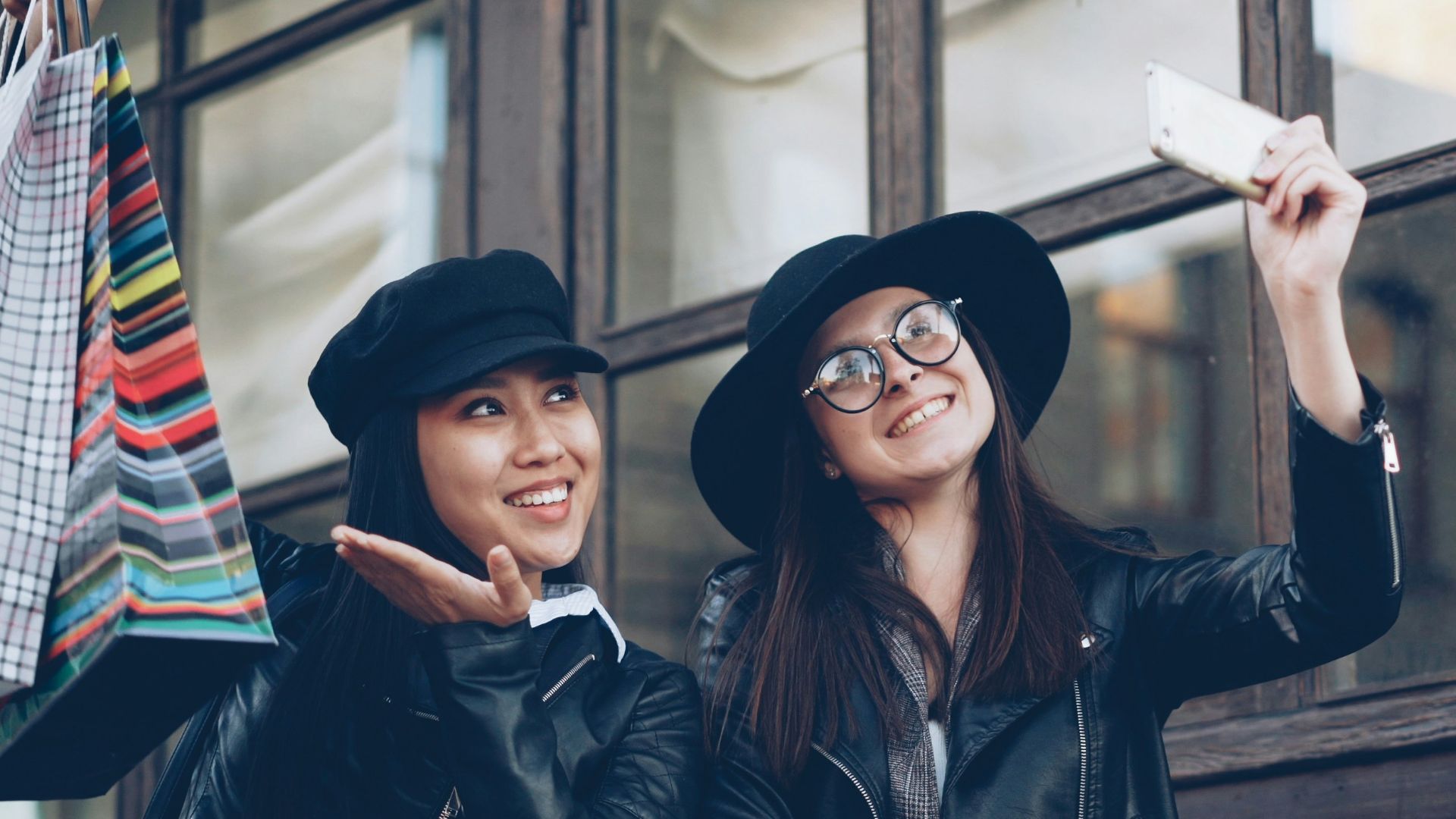 Two friends taking a selfie with shopping bags.