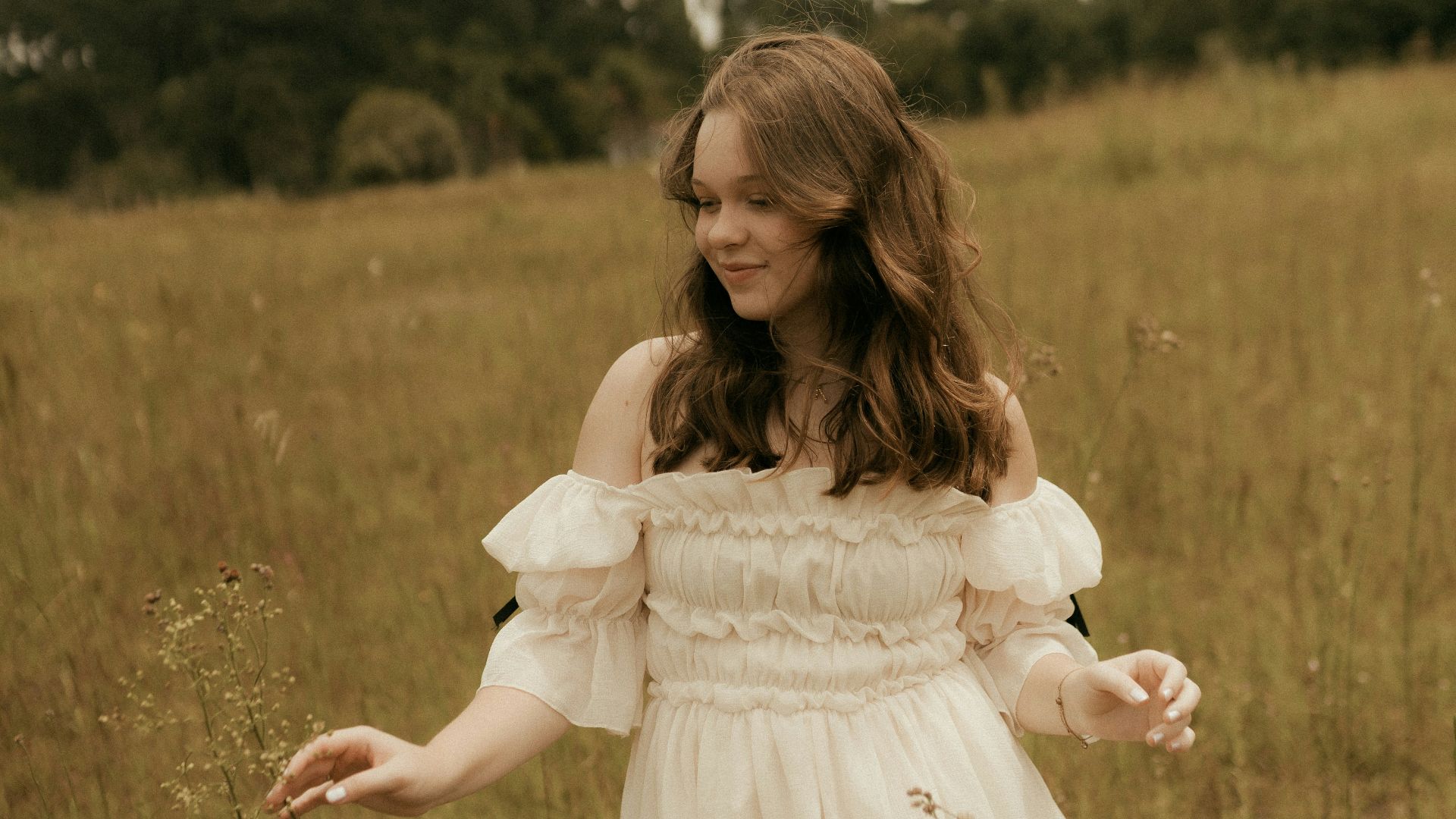 Young woman in a white dress in a grassy field.