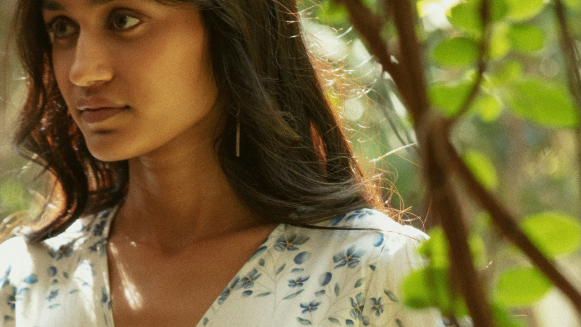 Woman in floral wrap dress among green leaves