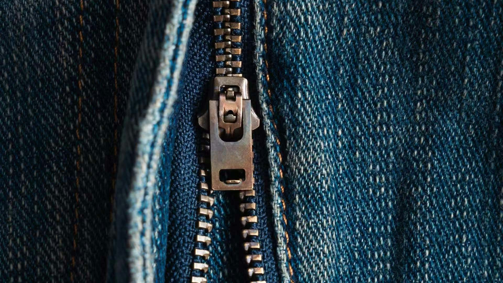 The zipper is partially opened on blue jeans.