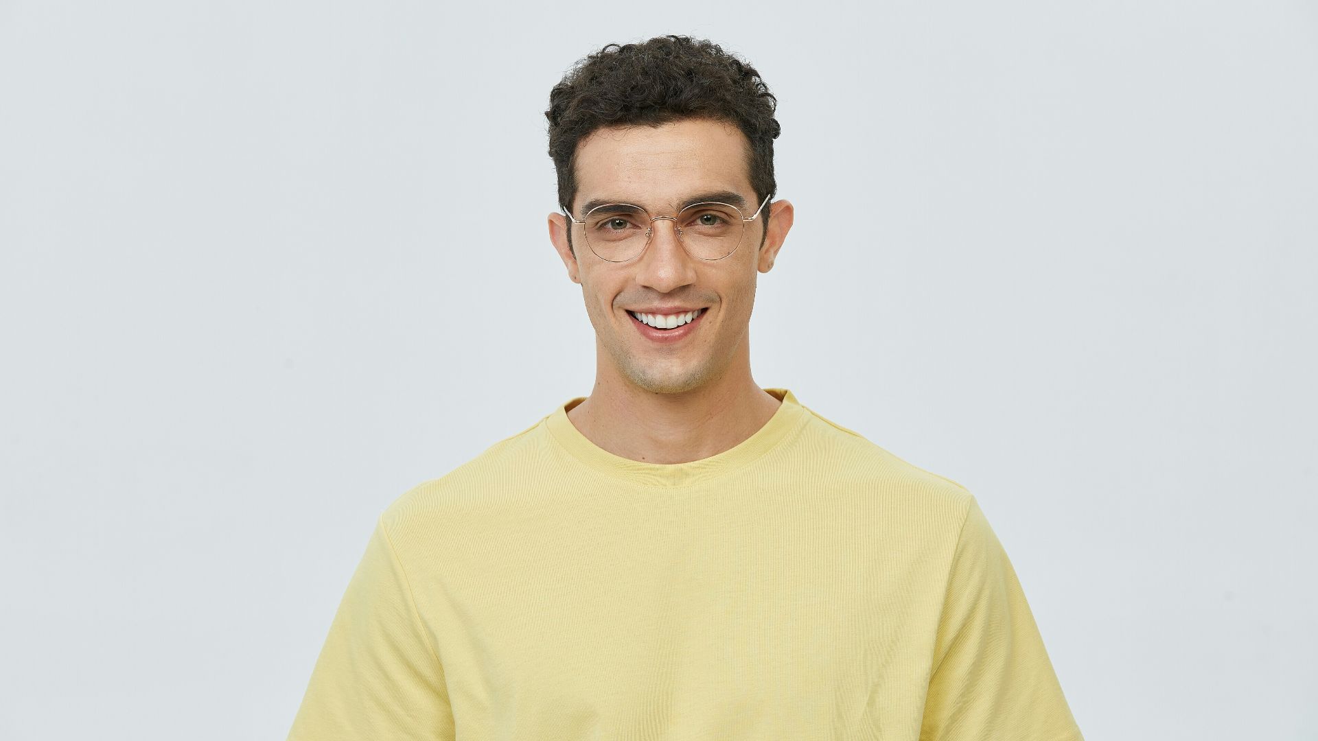 A man in a yellow t - shirt smiles at the camera