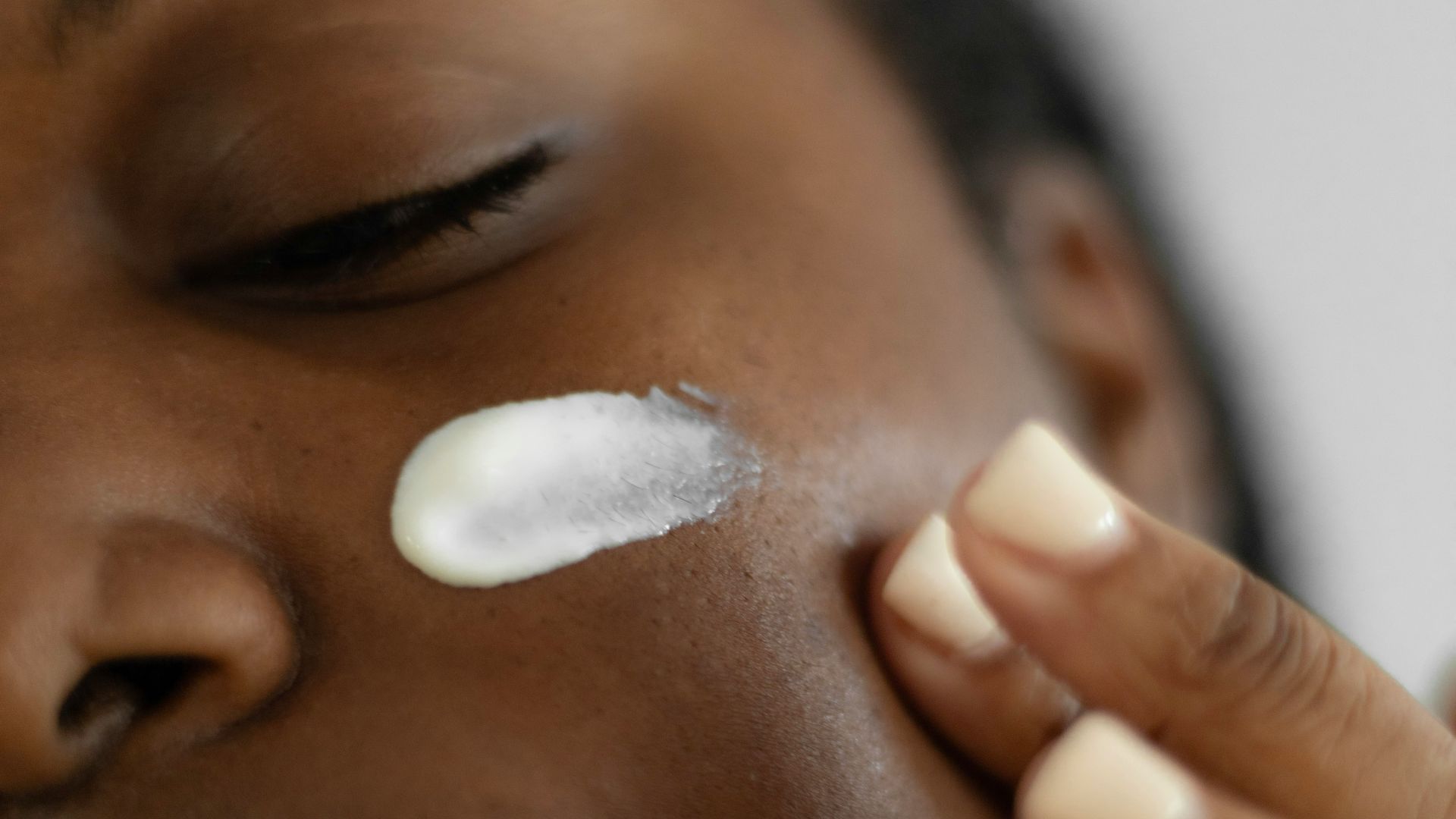 a woman is putting a lotion on her face