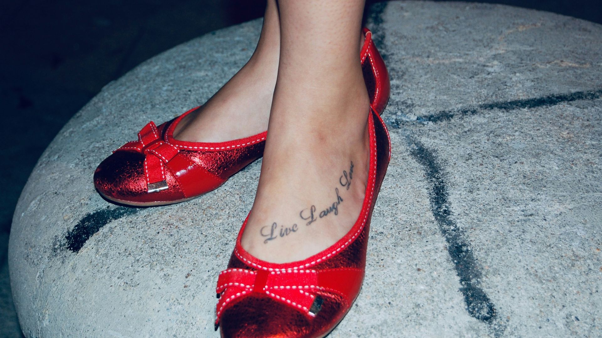 Red ballet flats with bows on a stone