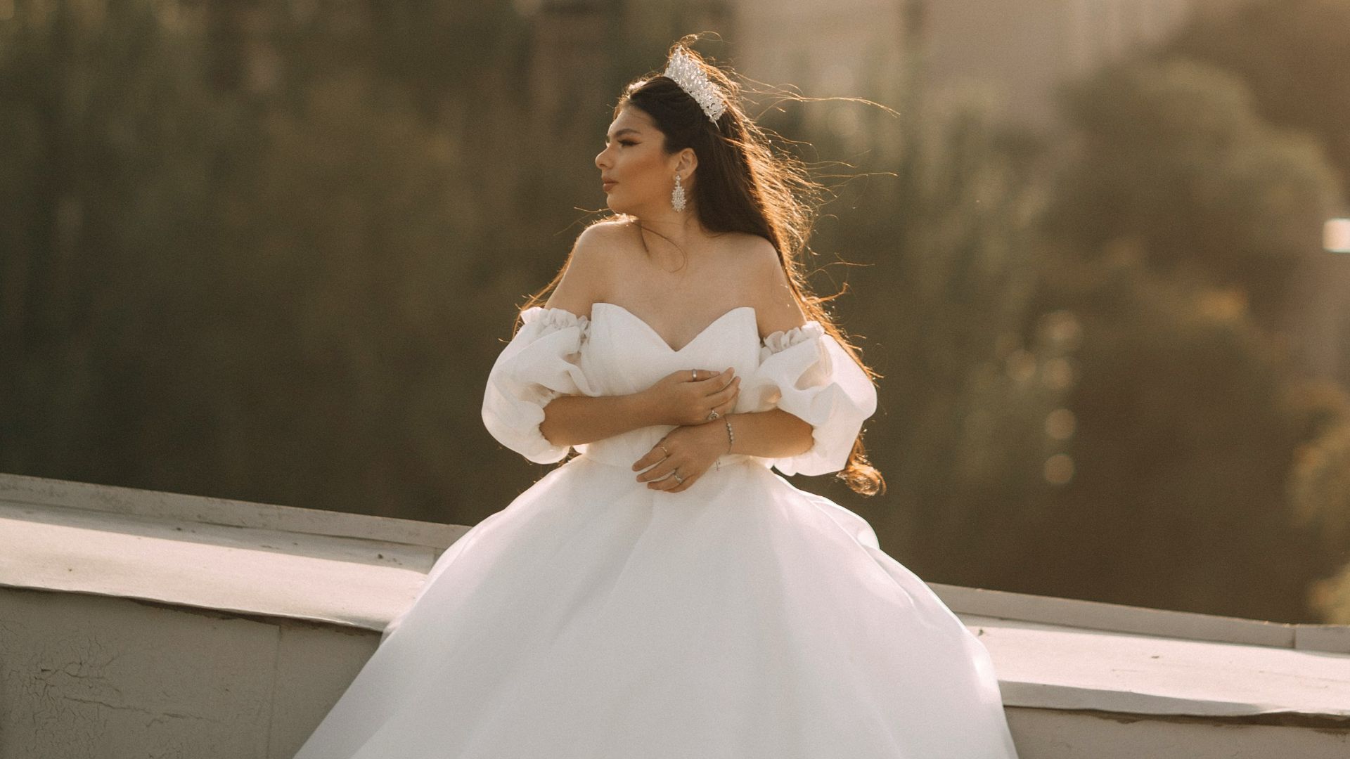 Bride poses in her wedding dress on a rooftop.