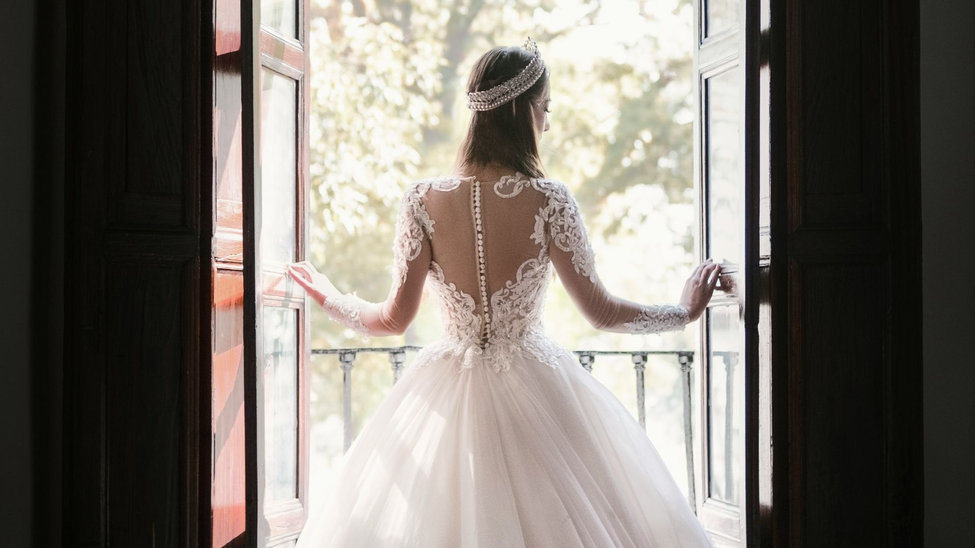 woman in white wedding dress standing near window during daytime