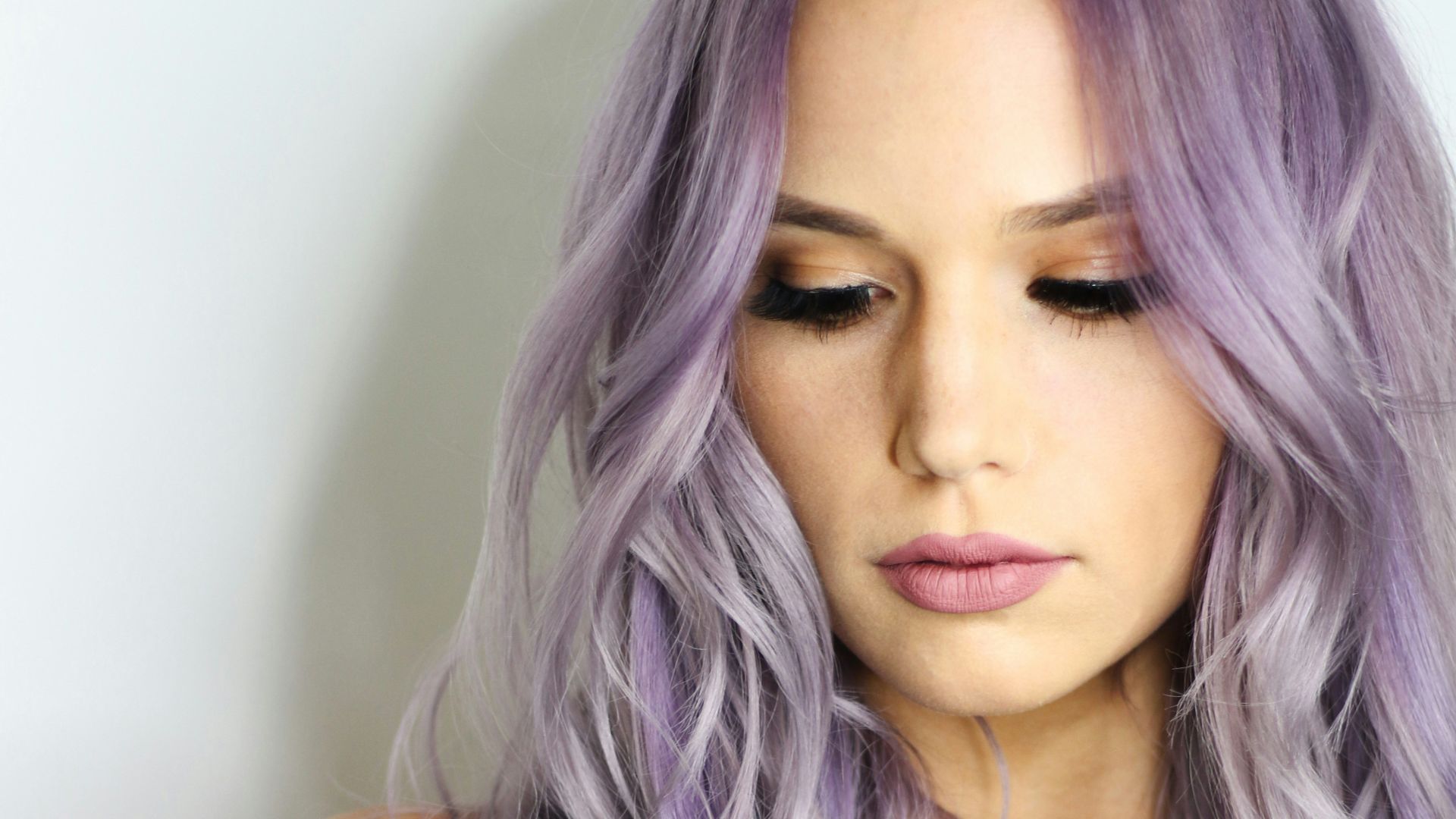 purple haired woman in black top leaning on wall