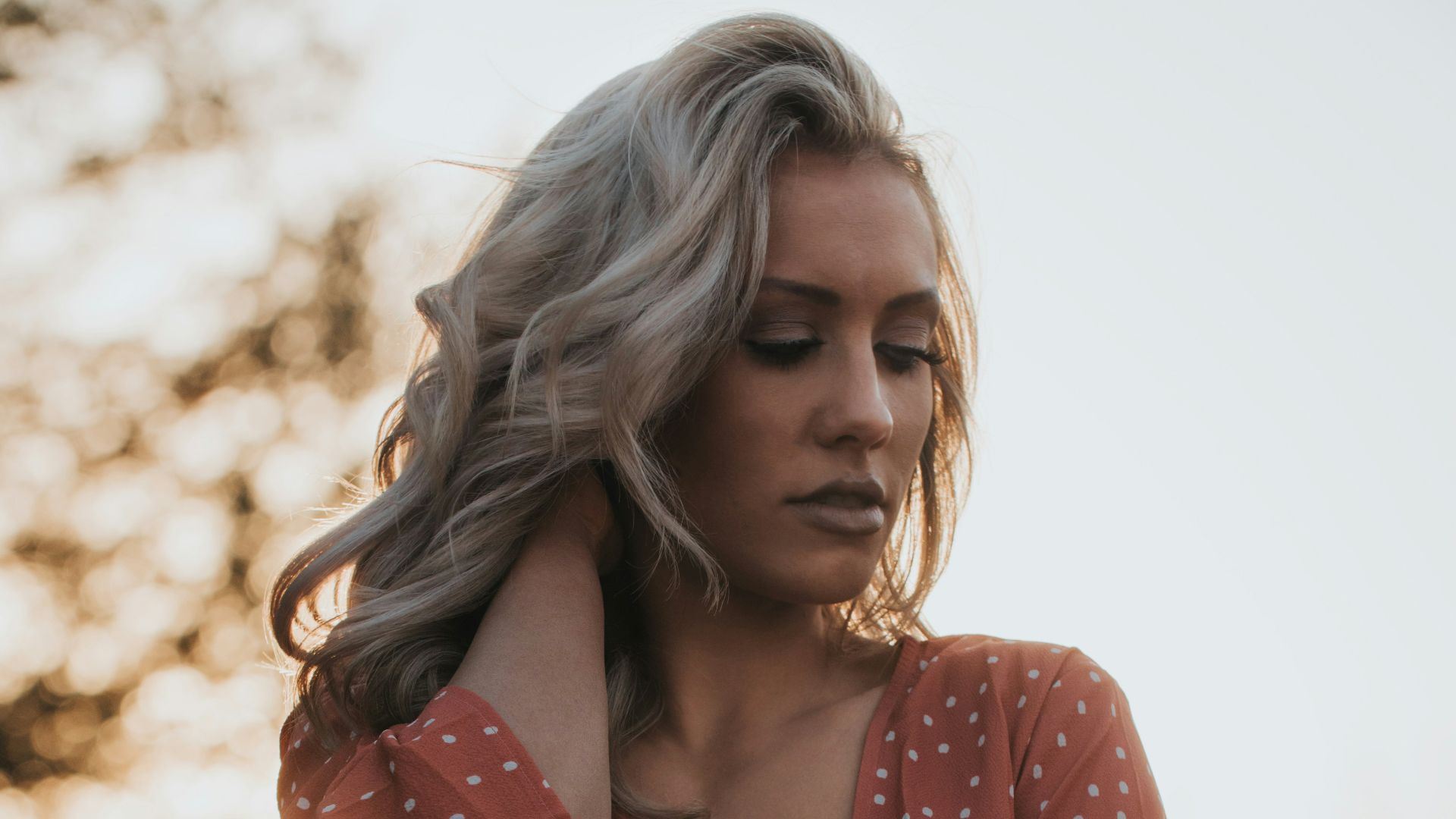 woman in white and red V-neck top holding her hair