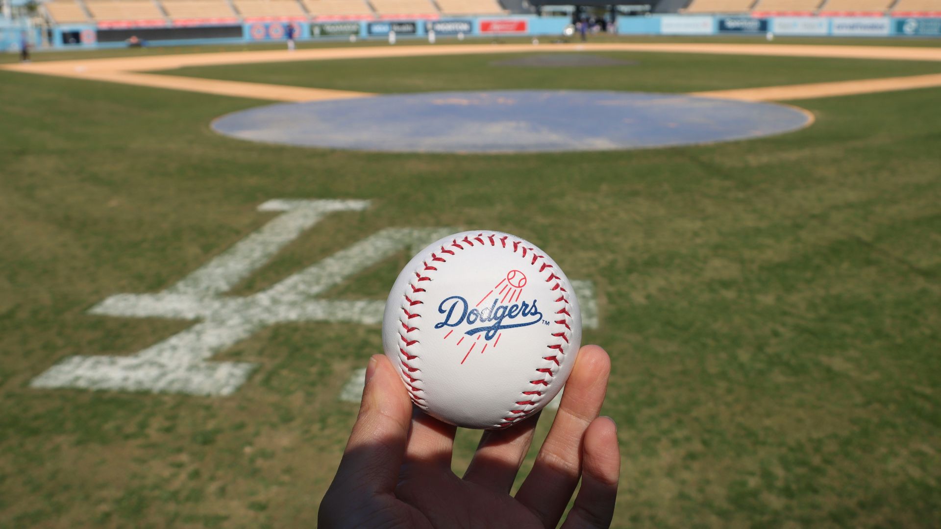 a person holding a baseball in front of a baseball field