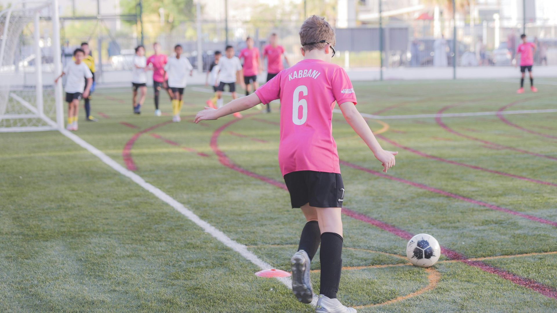 man in red and white soccer jersey kicking soccer ball during daytime