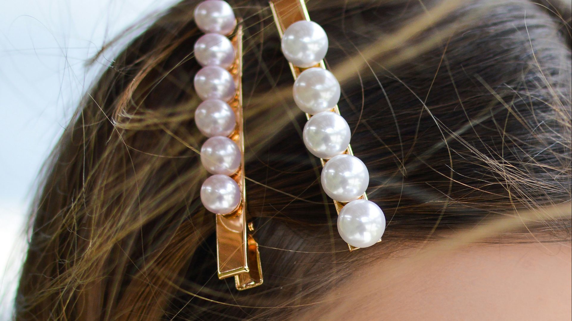 woman with two beaded clips clipped on her hair looking downwards