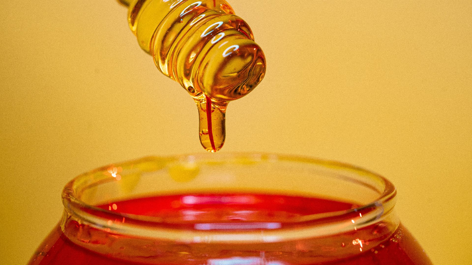clear glass bottle pouring red liquid on clear drinking glass