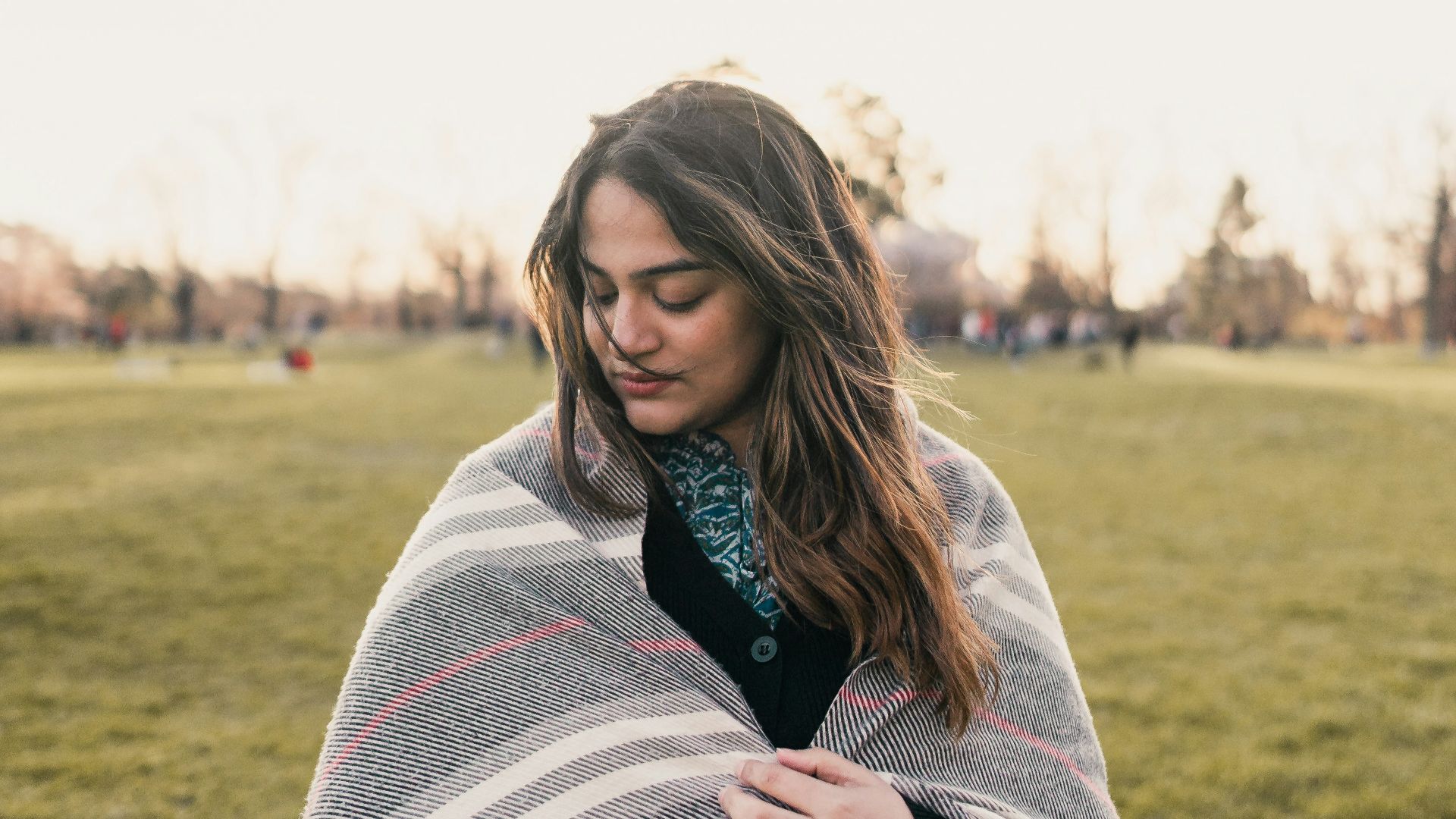 a woman wrapped in a blanket in a field