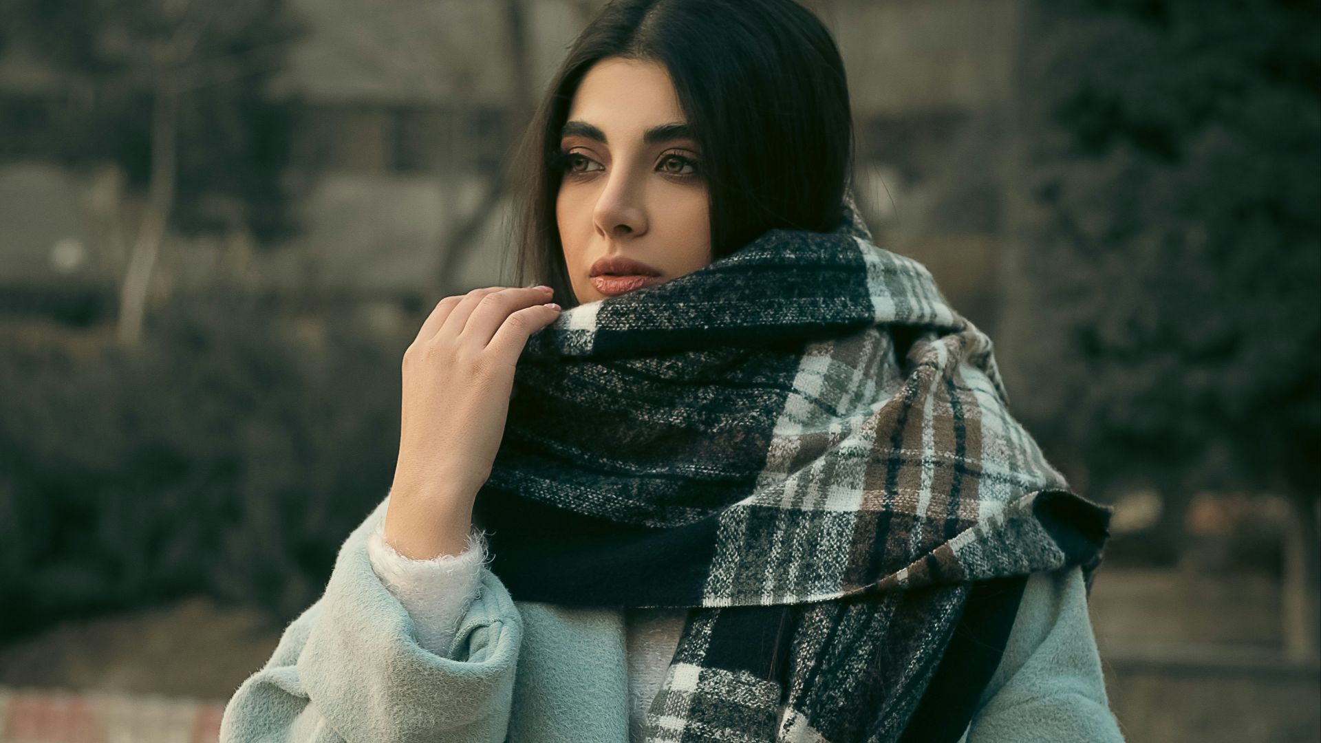 a woman wearing a blue coat and a plaid scarf