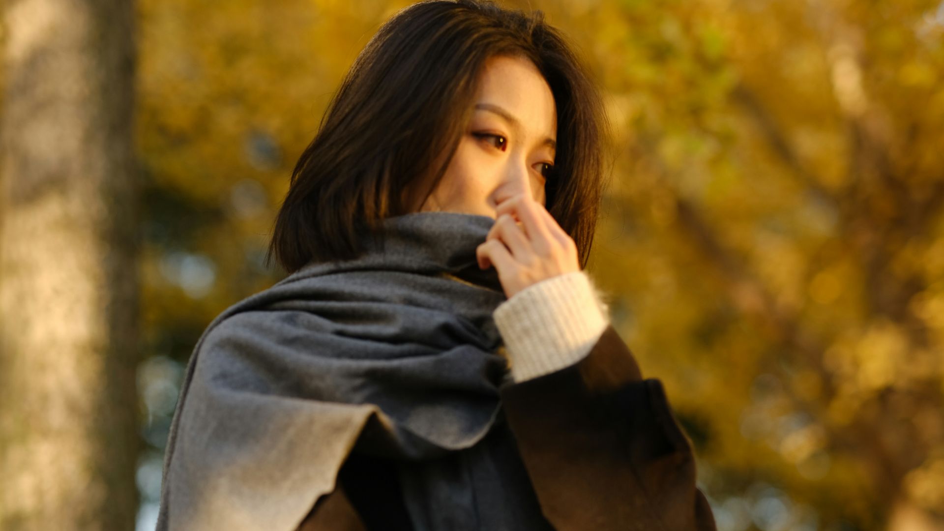 A woman standing in front of a tree talking on a cell phone