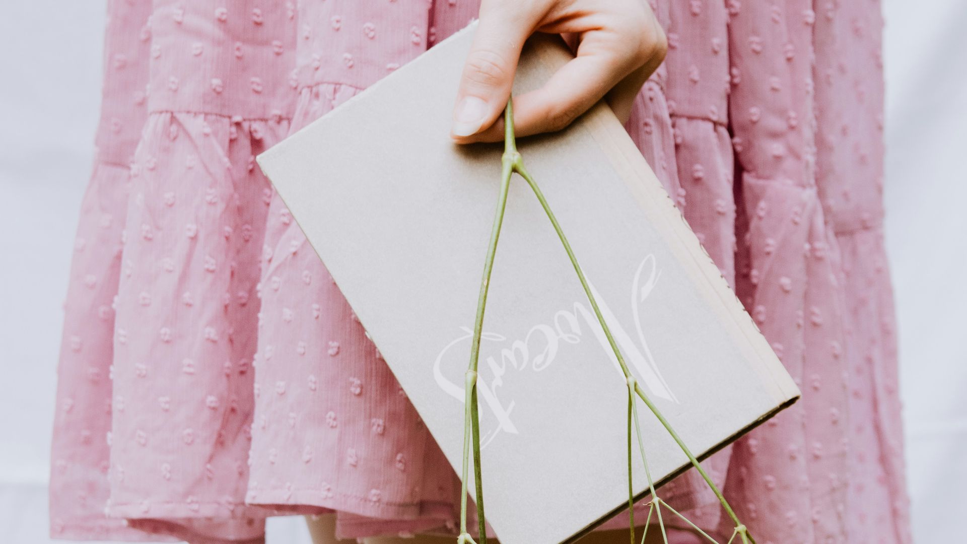a woman in a pink dress holding a card and flowers