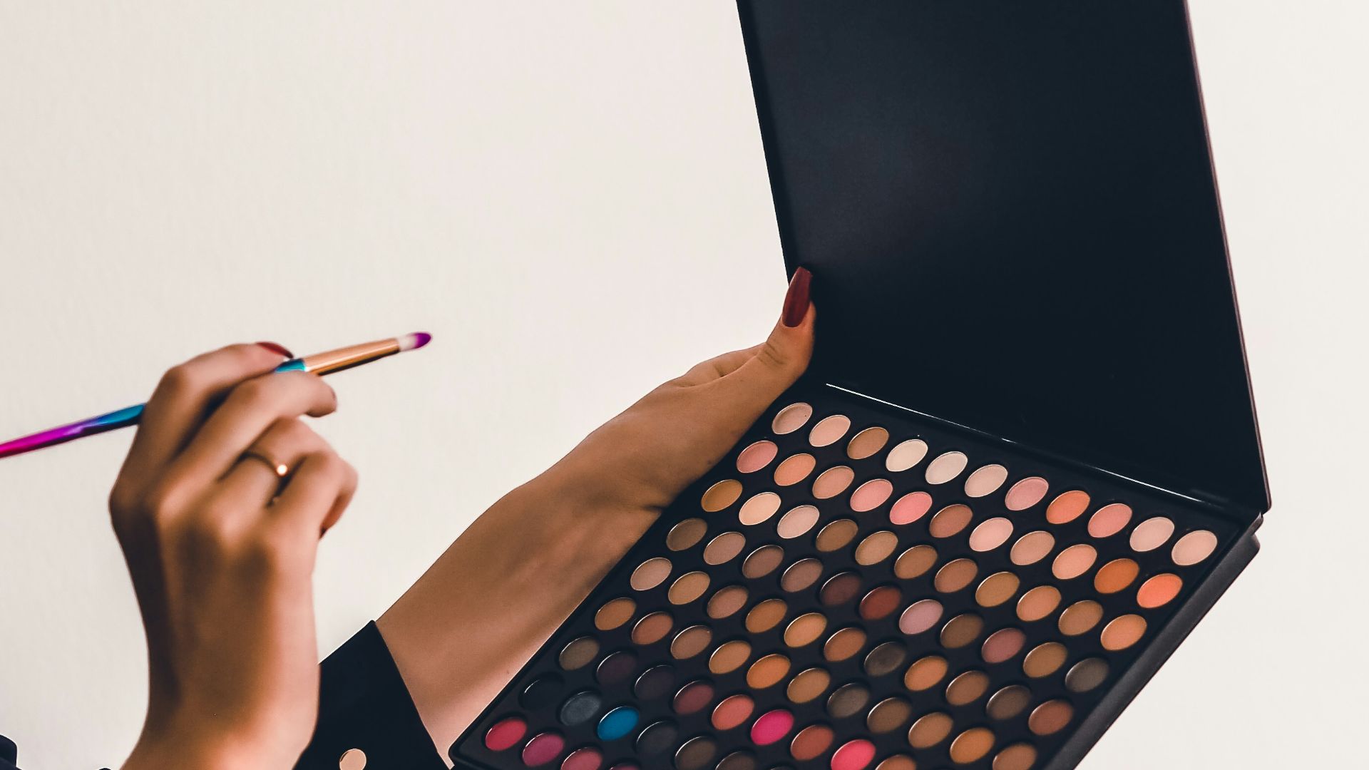a person holding a makeup palette and a pencil