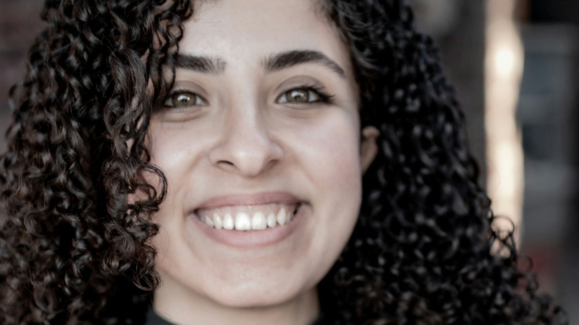 a woman with long curly hair smiling